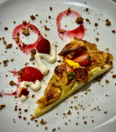 Part de dessert aux fruits rouges et crème, avec miettes et coulis sur assiette blanche à Bonnétable dans la Sarthe 72